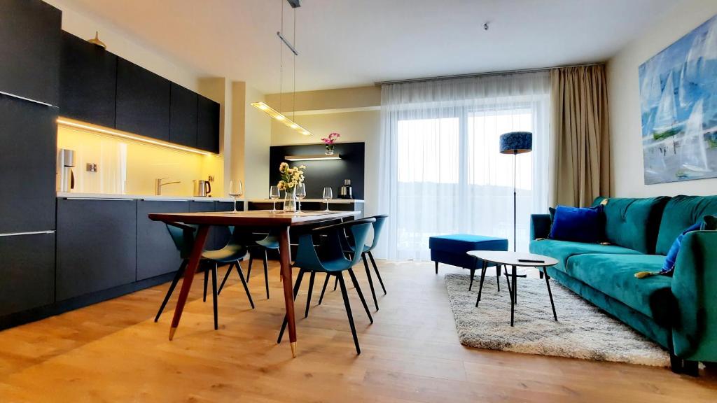 een woonkamer met een groene bank en een tafel bij Ferienwohnung A102 mit Komfort in Strandnähe mit Terrasse und Meerblick in 10ter Etage PARKING FREE in Międzyzdroje