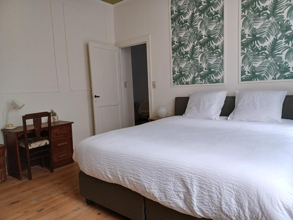 een slaapkamer met een groot wit bed en een bureau bij De Galerie - green leaves in Ieper