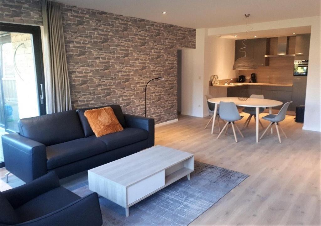 un soggiorno con divano e tavolo di Recreatiedomein Warredal - The Lodge a Neeroeteren