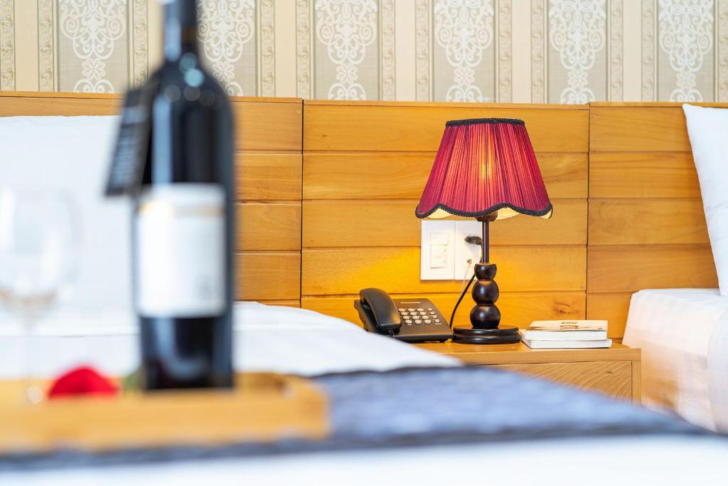 a bed with a phone and a lamp on a night stand at Dalat Wind Hotel in Da Lat