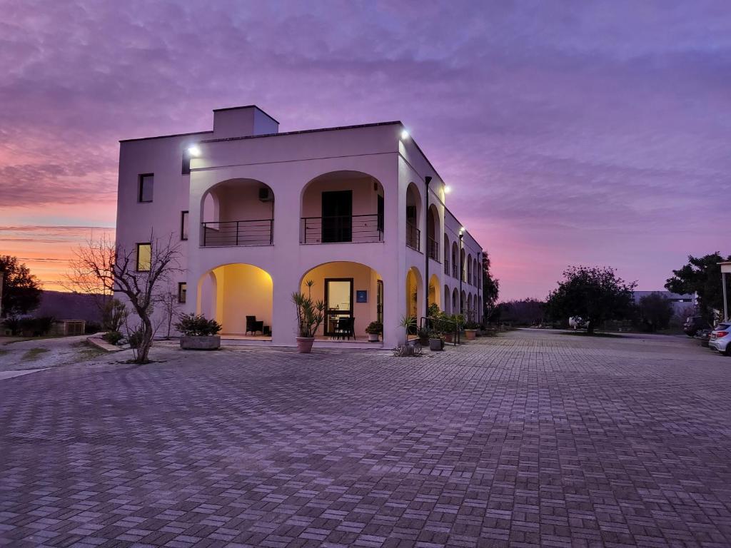 a large white building with a sunset in the background at Hotel Salento in Specchia