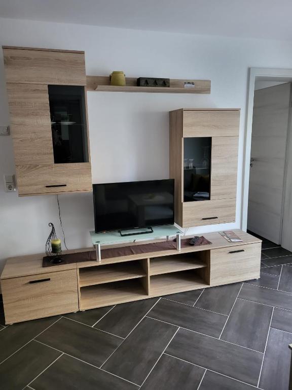 a living room with a television and wooden entertainment center at Gästewohnung 2 in Oschersleben