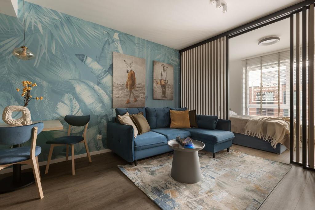 a living room with a blue couch and a bed at Glow Apartments, Gdańsk Śląska 12 in Gdańsk