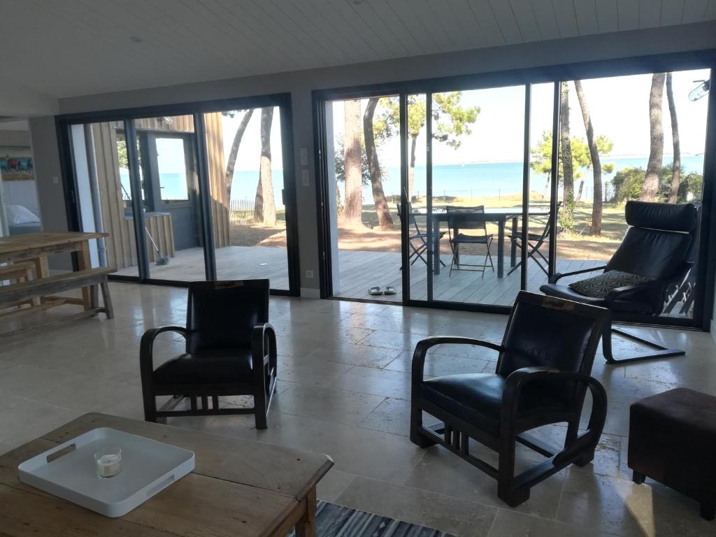 uma sala de estar com cadeiras e uma mesa e portas de vidro deslizantes em Villa Ile de Re avec acces mer du jardin em Rivedoux-Plage