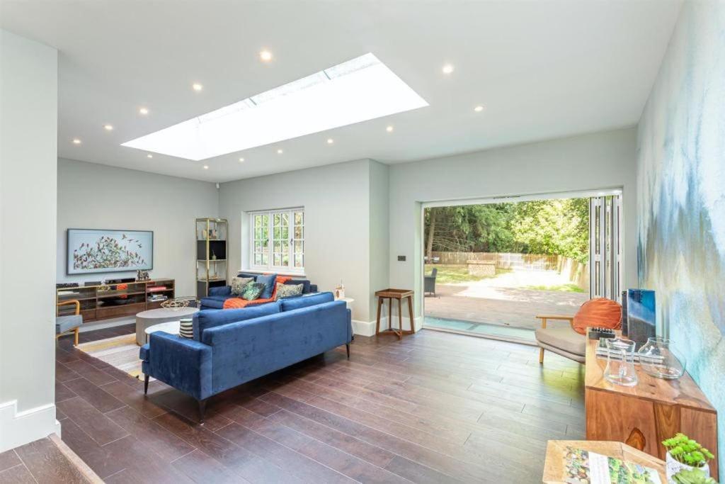 a living room with a blue couch and a large window at Stylish Home - Wentworth, Sunningdale Golf Club in Sunninghill