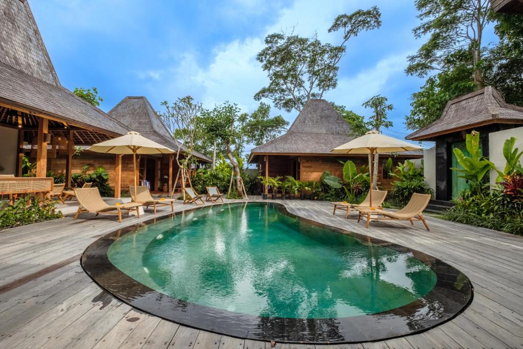 - une piscine dans un complexe avec des chaises et des parasols dans l'établissement Kaju Apartment by Hombali, à Canggu