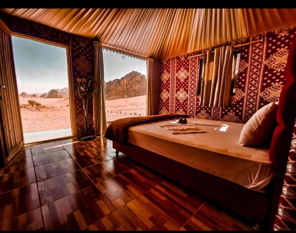 a bedroom with a bed with a view of the desert at Maraheb Luxury camp in Wadi Rum