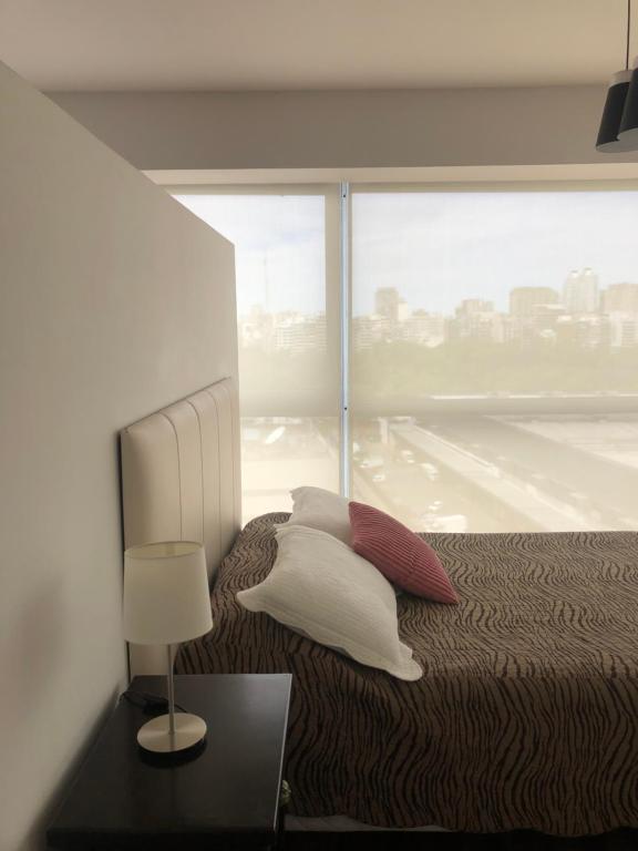 um quarto com uma cama e uma janela grande em Apartamento Av kennedy y Cerviño a metros embajada EEUU em Buenos Aires