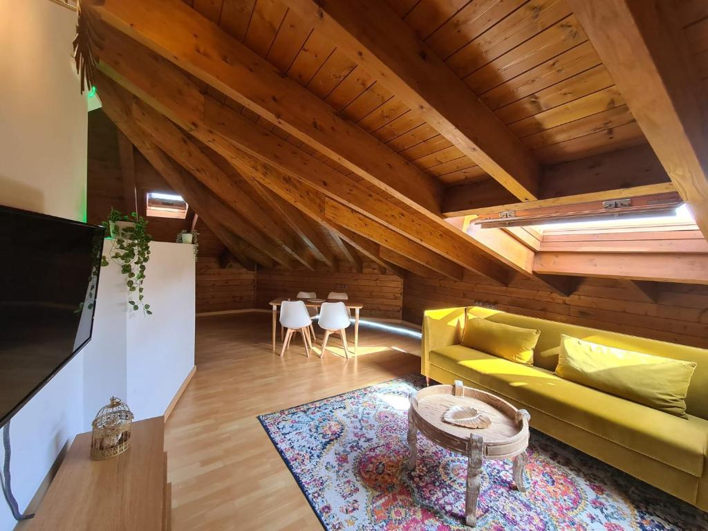 a living room with a yellow couch and a table at Dos Torres Ático abuhardillado en Calle Alfonso I in Zaragoza