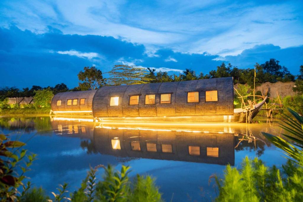 a house on the water at night at Mekong Silt Ecolodge - Swimming Pool & Free Breakfast in Can Tho