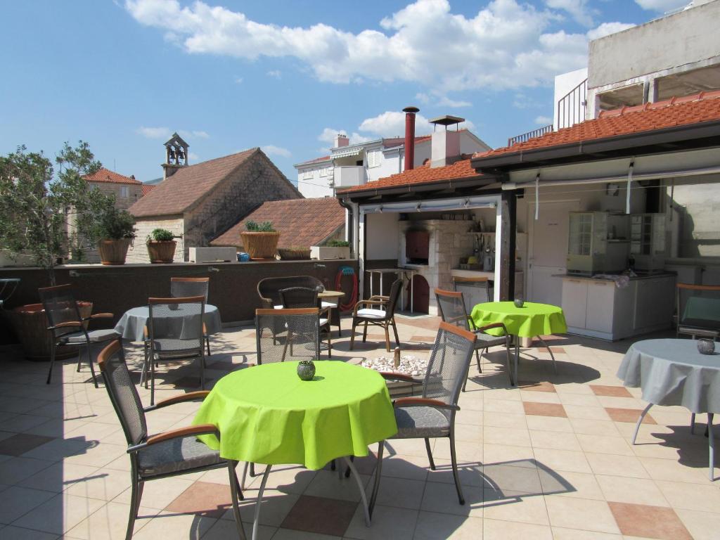 een patio met tafels en stoelen met groene tafels bij Guest House Klaudija in Trogir