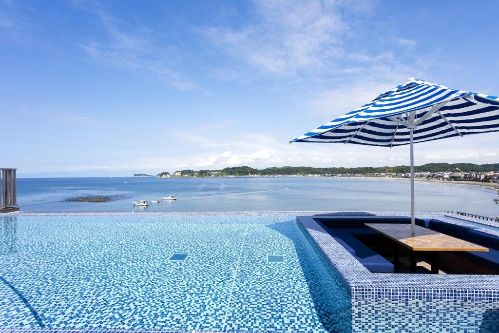 a swimming pool with a table and an umbrella at THE HARBOR TERRACE in Kotsubo