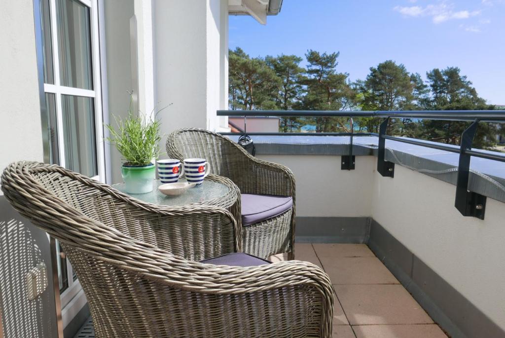 a balcony with wicker chairs and a table with cups at Haus Meeresblick FeWo Strandperle in Baabe