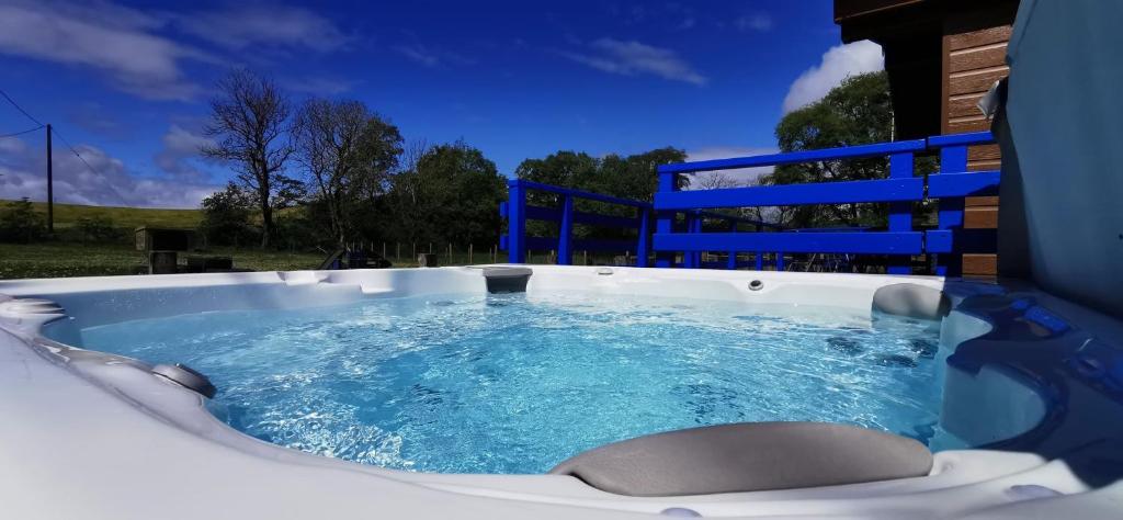 uma banheira de hidromassagem com água azul em Glen Roe - 3 Bed Lodge on Friendly Farm Stay with Private Hot Tub em New Cumnock