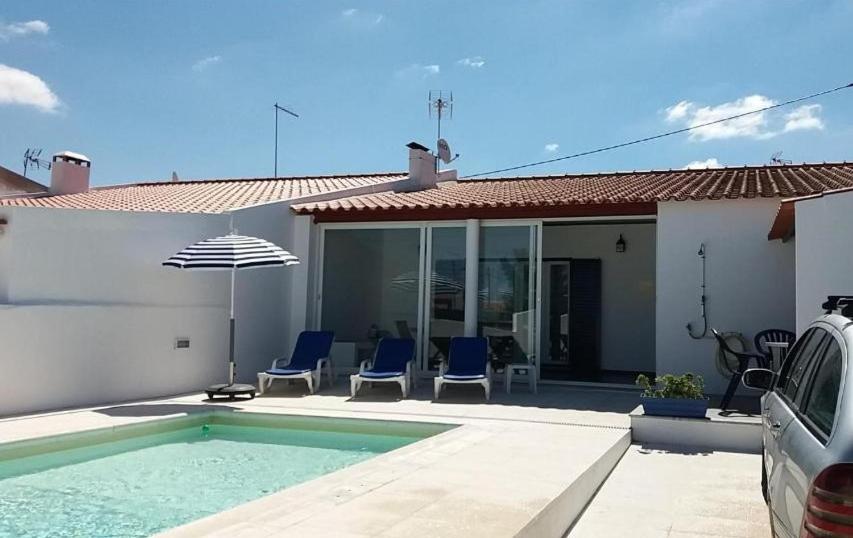 een huis met een zwembad met stoelen en een parasol bij Villa Caballero in Alfundão