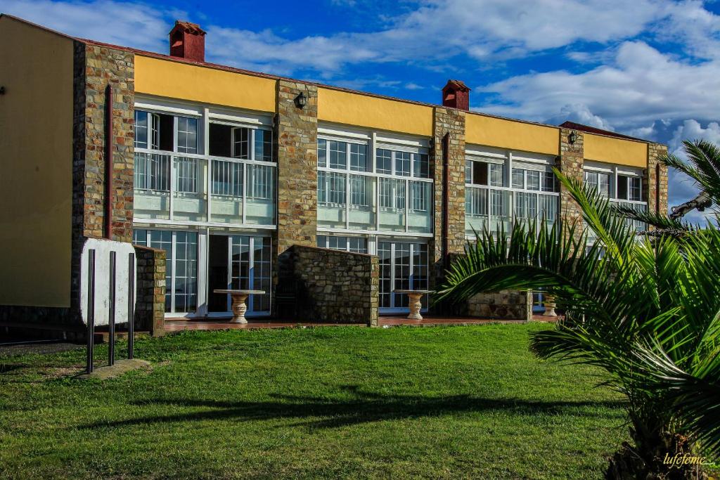 un edificio con una palmera delante en La Morada del CABO PEÑAS EL FARO - Gozón - Luanco, en Ferrero