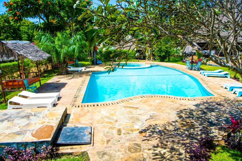 a swimming pool in a yard with chairs and trees at Oasis Diani Beach Villas in Diani Beach