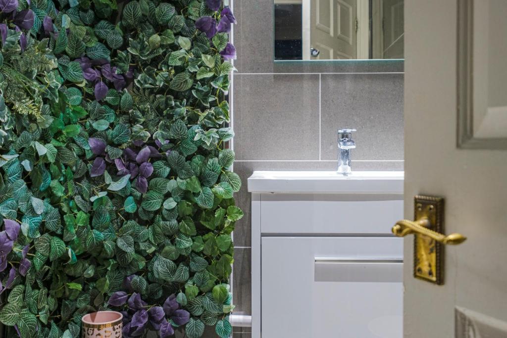 a bathroom with a green wall next to a sink at Larger Groups Apartment with Garden and Parking in London