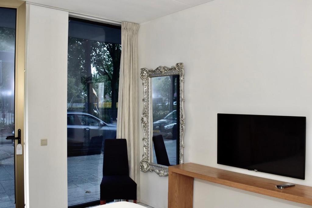 een woonkamer met een tv en een spiegel bij 010 Studio City Center Rotterdam in Rotterdam