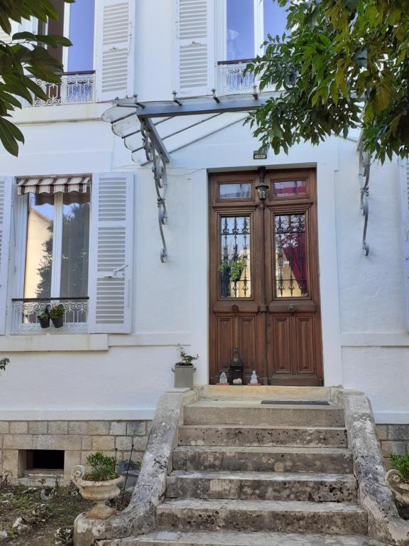 Casa blanca con puerta de madera y escaleras en Chambres d'hôtes de Flo, en Brosses