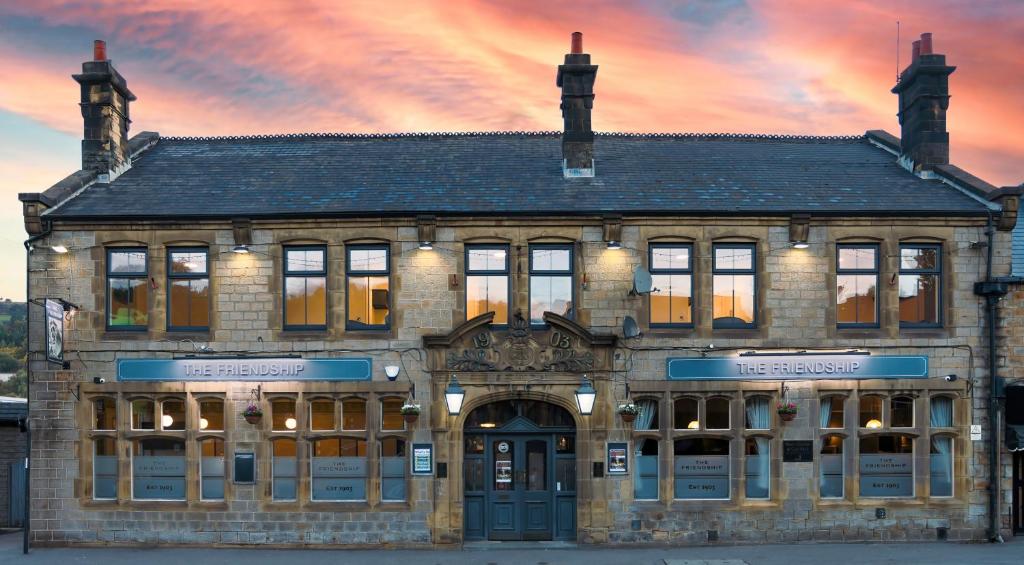 a large brick building with a sunset in the background at The Friendship Hotel in Stocksbridge