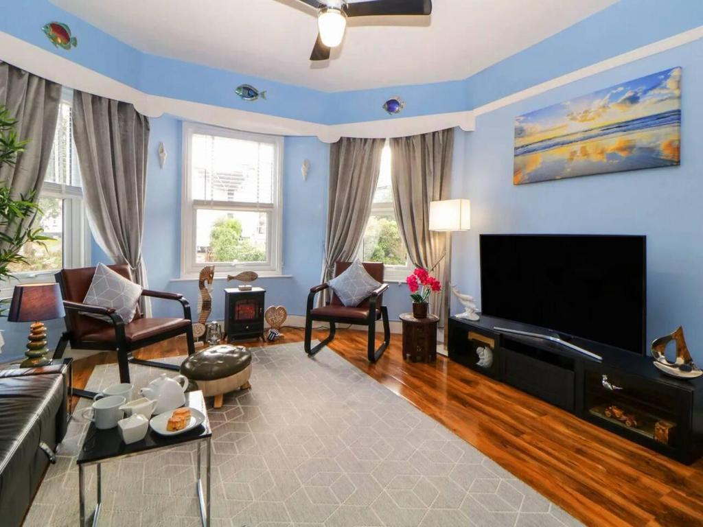 ein Wohnzimmer mit blauen Wänden und einem Flachbildfernseher in der Unterkunft English Riviera coastal holiday home in Devon Uk in Paignton