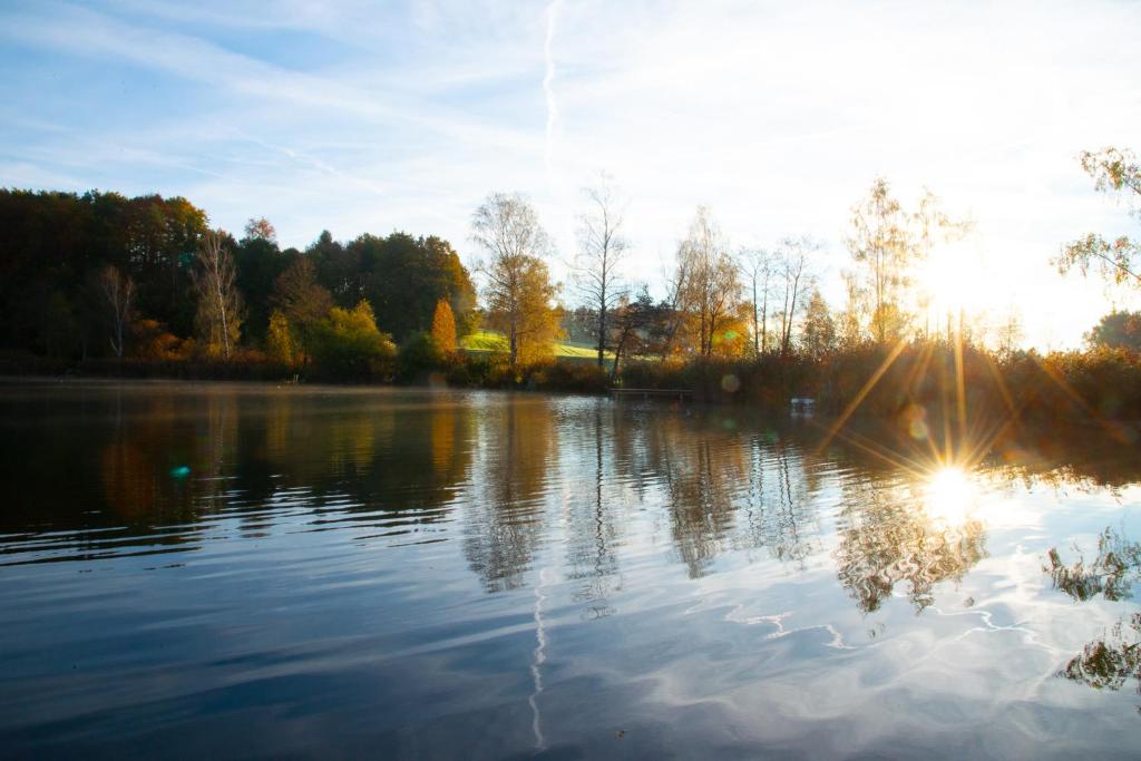 a lake with the sun reflecting on the water at Seehof direkt am See mit privatem Seezugang 