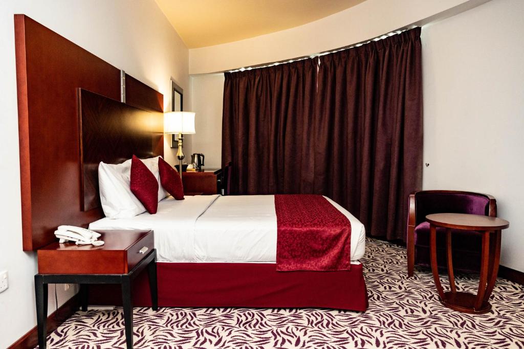um quarto de hotel com uma cama e uma cadeira em MRA Grand Hotel em Dubai