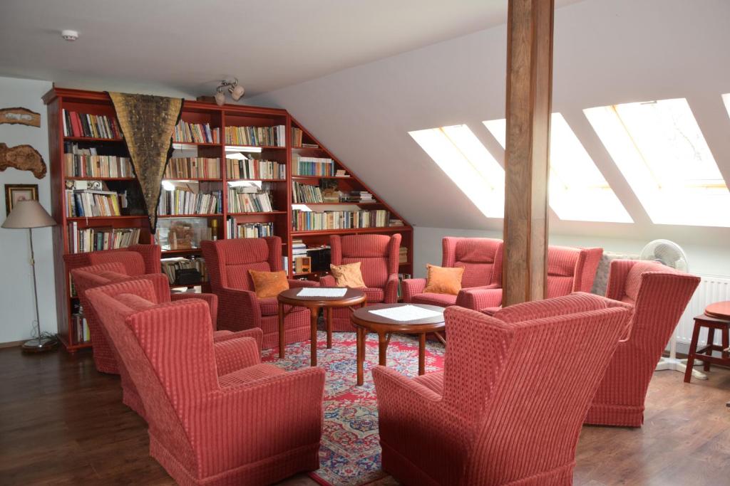 eine Bibliothek mit roten Stühlen, Tischen und Bücherregalen in der Unterkunft Holló és Bárány Vendégház in Herend