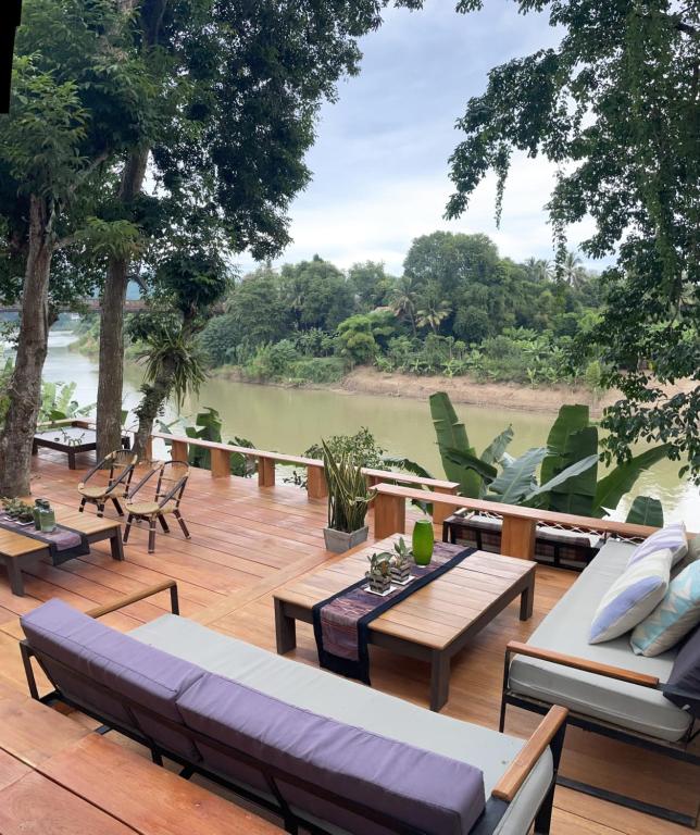 a deck with couches and tables and a view of a river at Moonlight Champa Riverview in Luang Prabang