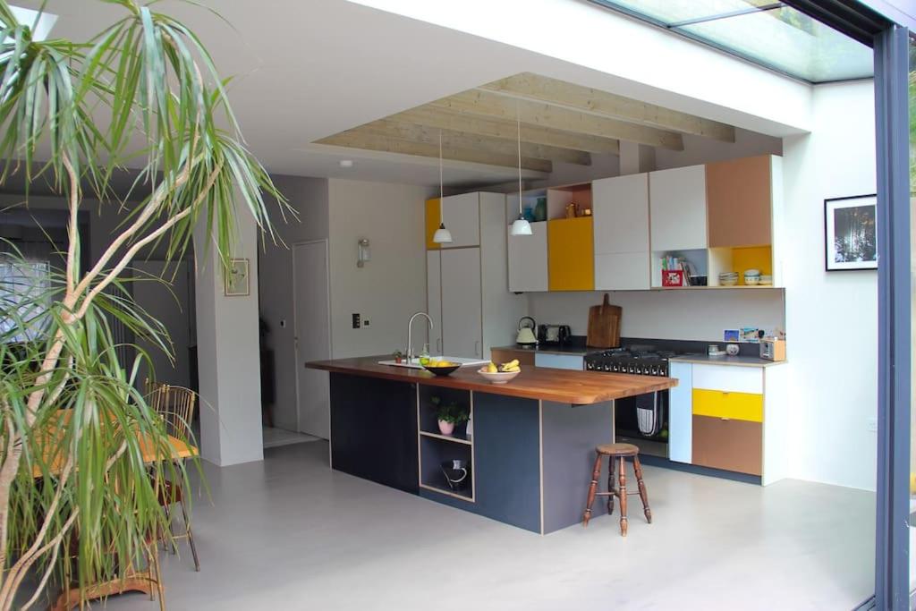 a kitchen with yellow and white cabinets and a island at Large, modern, light, open plan designer house in London
