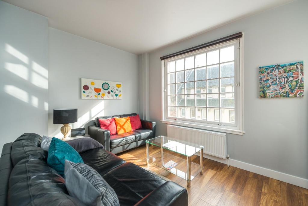 エディンバラにあるRoyal Mile Modern Apartmentのリビングルーム(黒い革張りのソファ、窓付)
