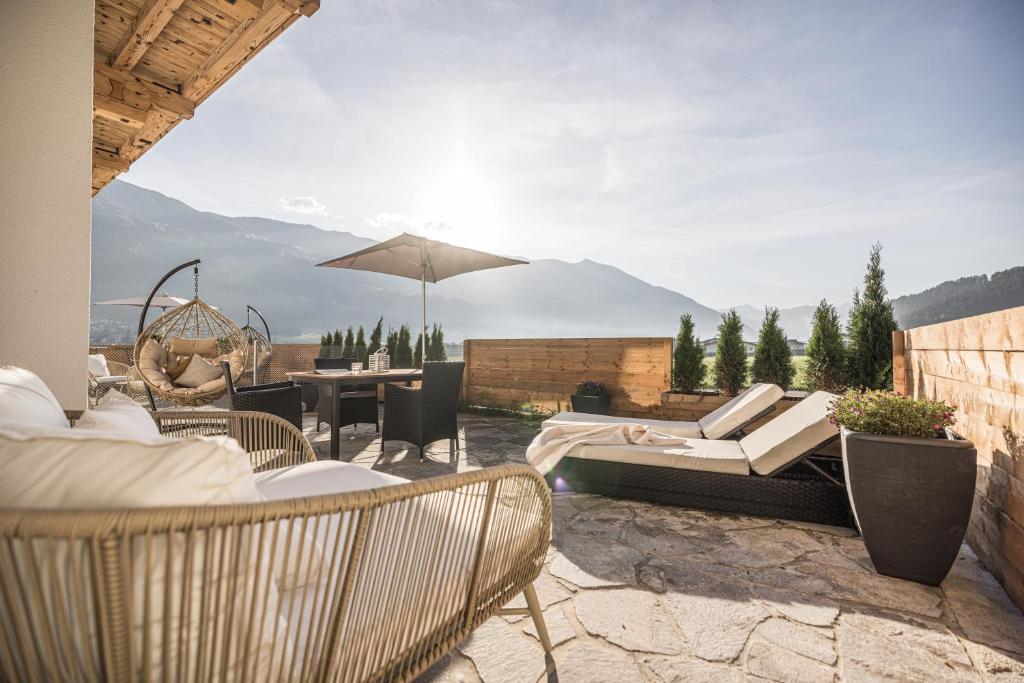 a patio with a table and chairs and an umbrella at MaxStudio Premium Apartment Zillertal mit Bergblick in Schlitters