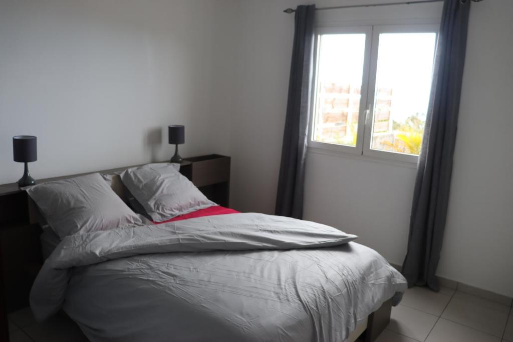 a bed in a bedroom with a window at Le Sandivel in Saint-Denis