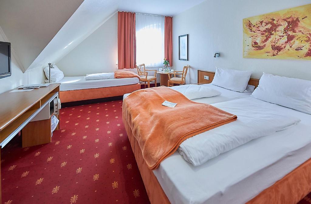 ein Hotelzimmer mit einem großen Bett und einem Schreibtisch in der Unterkunft Hotel Diamant in Wedel