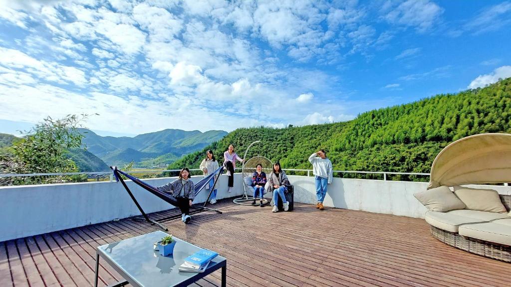 a group of people standing on a balcony with a view of mountains at Moganshan Naicang Boutique Hotel in Deqing