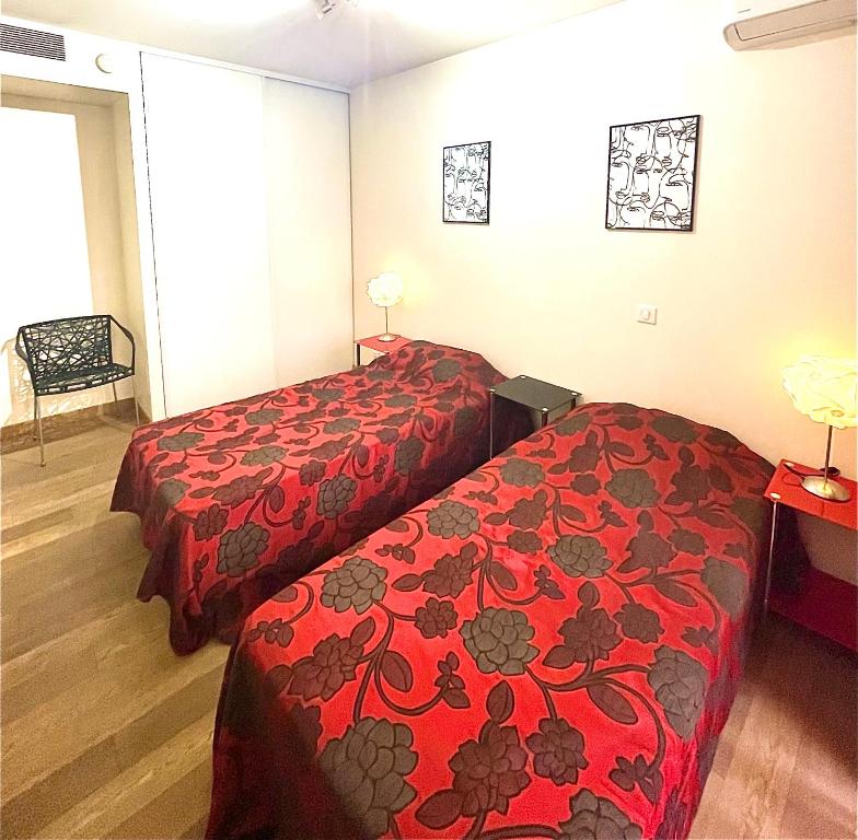 Cette chambre d'hôtel comprend 2 lits avec des couvertures rouges. dans l'établissement Jolie 3 pièces avec terrasse au vieux port, à 2 pas des plages et du palais., à Cannes