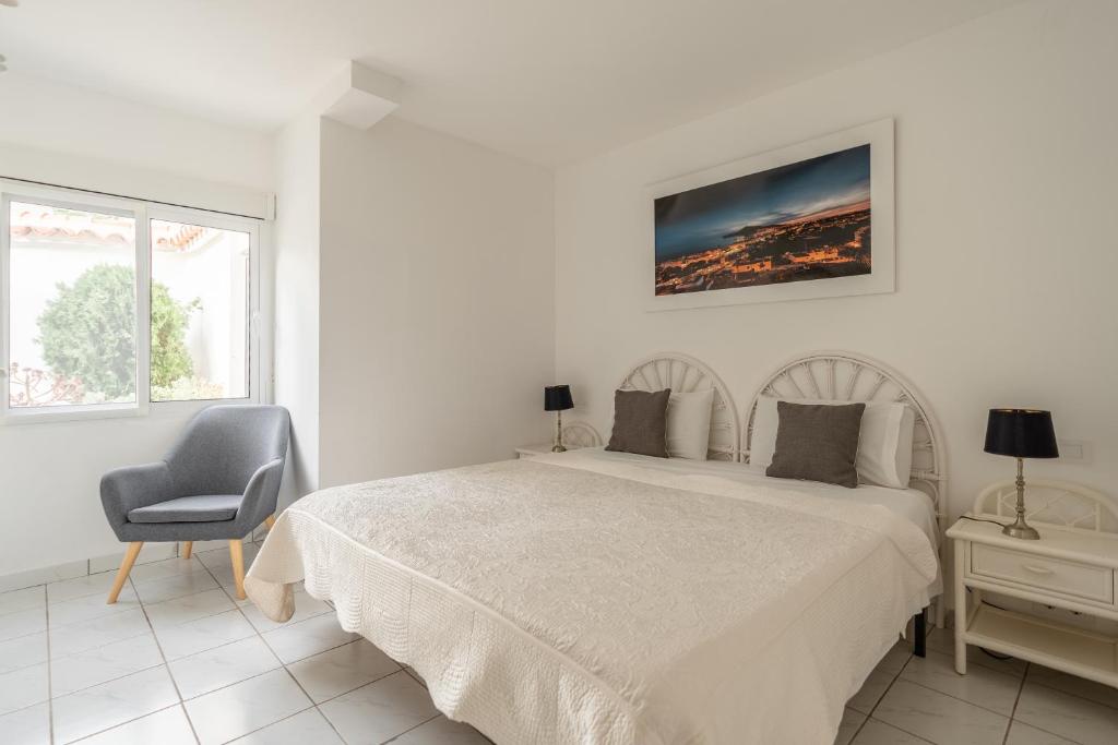 a white bedroom with a bed and a chair at Maryvilla Inspiración y Vacaciones - Bungalows in Calpe