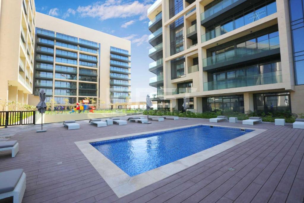 a building with a swimming pool in front of a building at Beautiful 1 Bedroom at Soho Square at Al Saadiyat Island in Abu Dhabi
