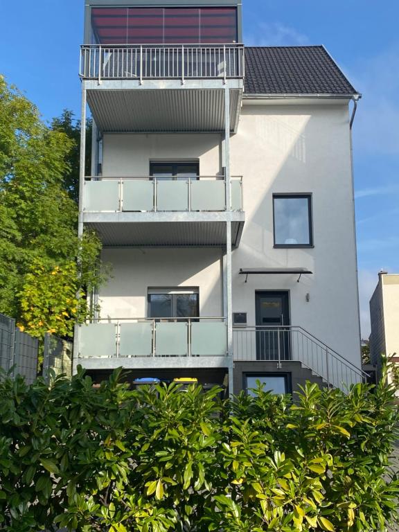 a white apartment building with balconies and trees at Ferienwohnung LIVONA in Bad Neuenahr-Ahrweiler