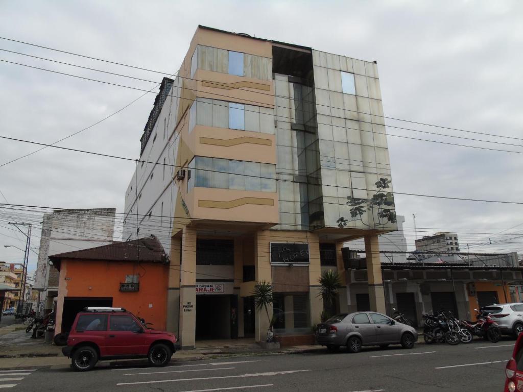un edificio alto con coches estacionados frente a él en Hotel Queens, en Guayaquil