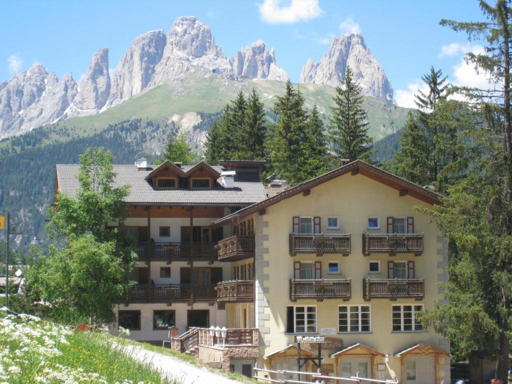 a hotel in the mountains with mountains in the background at Hotel Majon Miramonti in Canazei