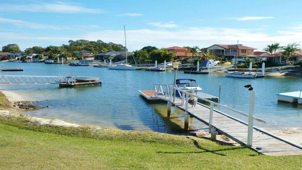 a dock with boats in a marina with houses at 1 - 57 Witonga Drive, Yamba in Yamba