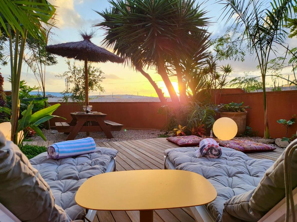 um pátio com sofás e mesas e um guarda-chuva em MEDANO4YOU La Terraza De Isa em La Tejita