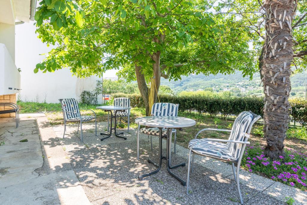 a group of chairs and a table under a tree at Apartment Violet with a garden in Jurandvor