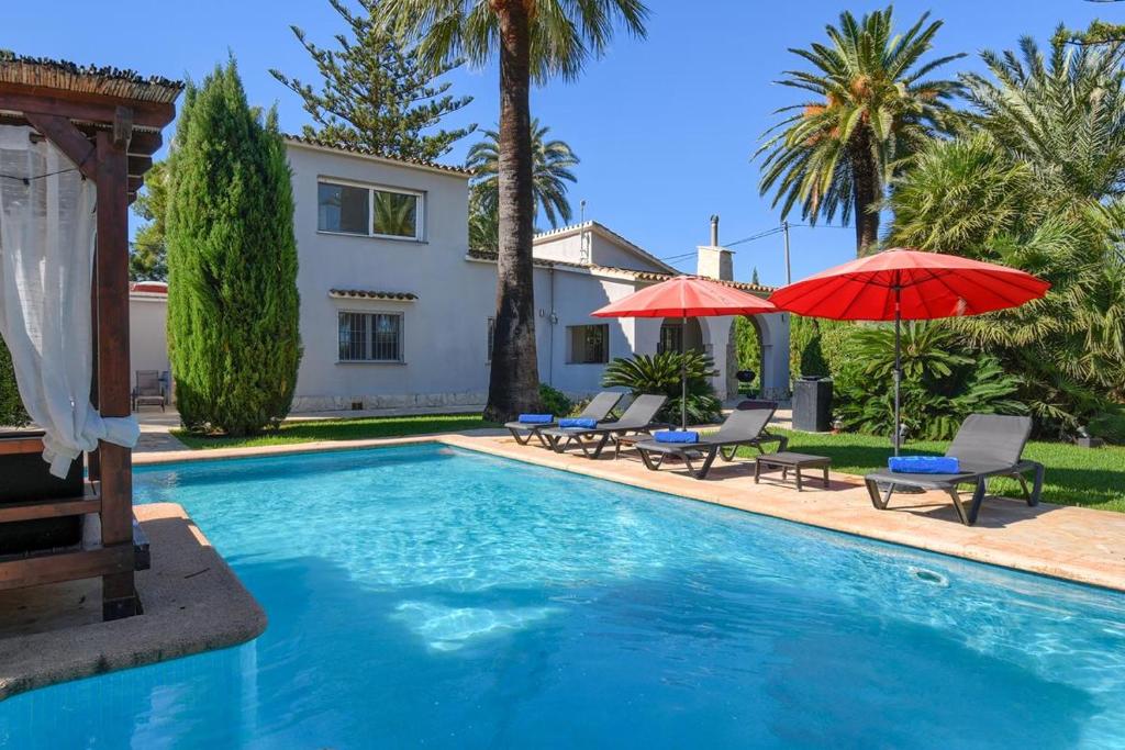 una piscina con sillas y sombrillas y una casa en Las Marinas 8, en Denia