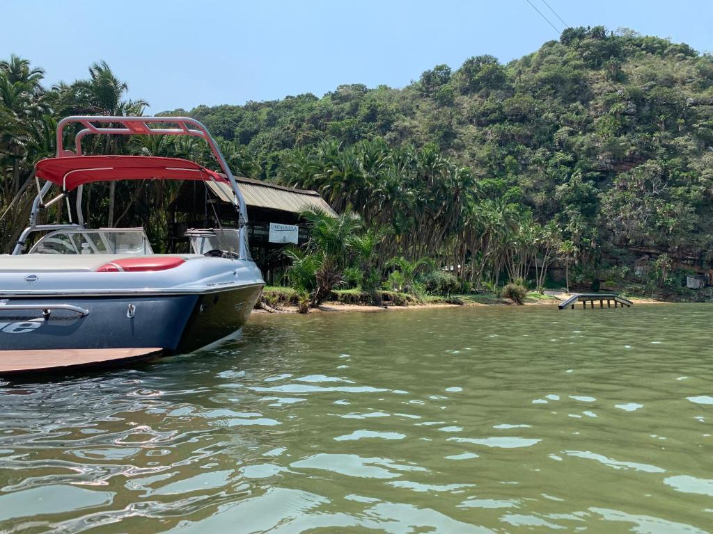 um barco sentado na água ao lado de uma casa em Umtamvuna River Lodge em Port Edward