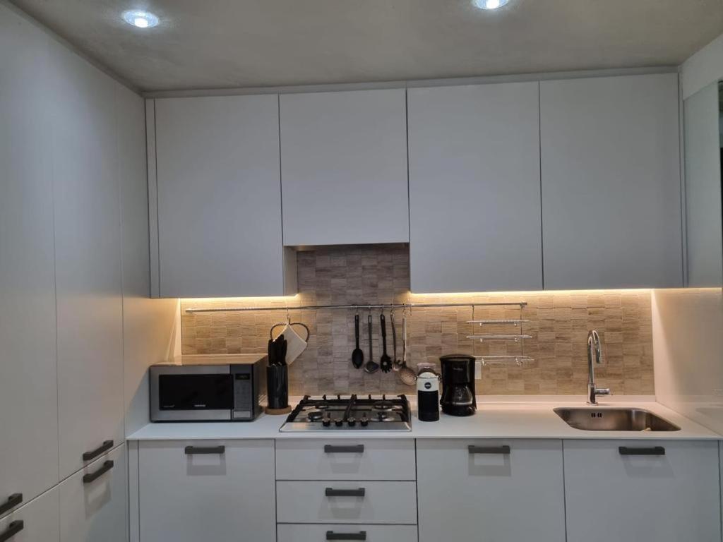 a kitchen with white cabinets and a sink and a microwave at Appartamento ORCHIDEA a Sirmione sul Lago di Garda con piscina, giardino e spiaggia con molo in Sirmione