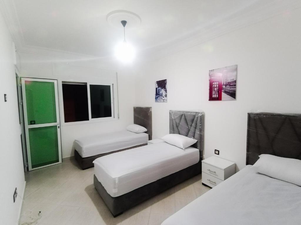 una camera con due letti e due finestre di NOUVEAU Appartement Totalement neuf - très propre à coté du centre commercial MARJANE a Tangeri