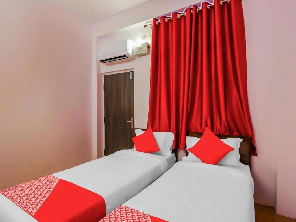 2 camas en una habitación con cortinas rojas en HZ INN en Hyderabad